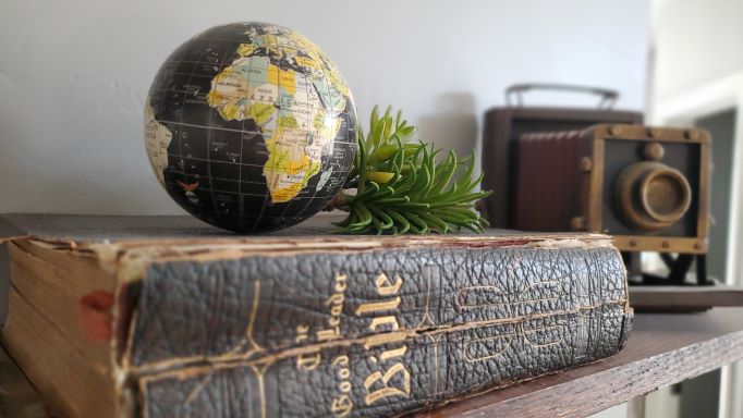 picture of a globe, bible and camera on a shelf